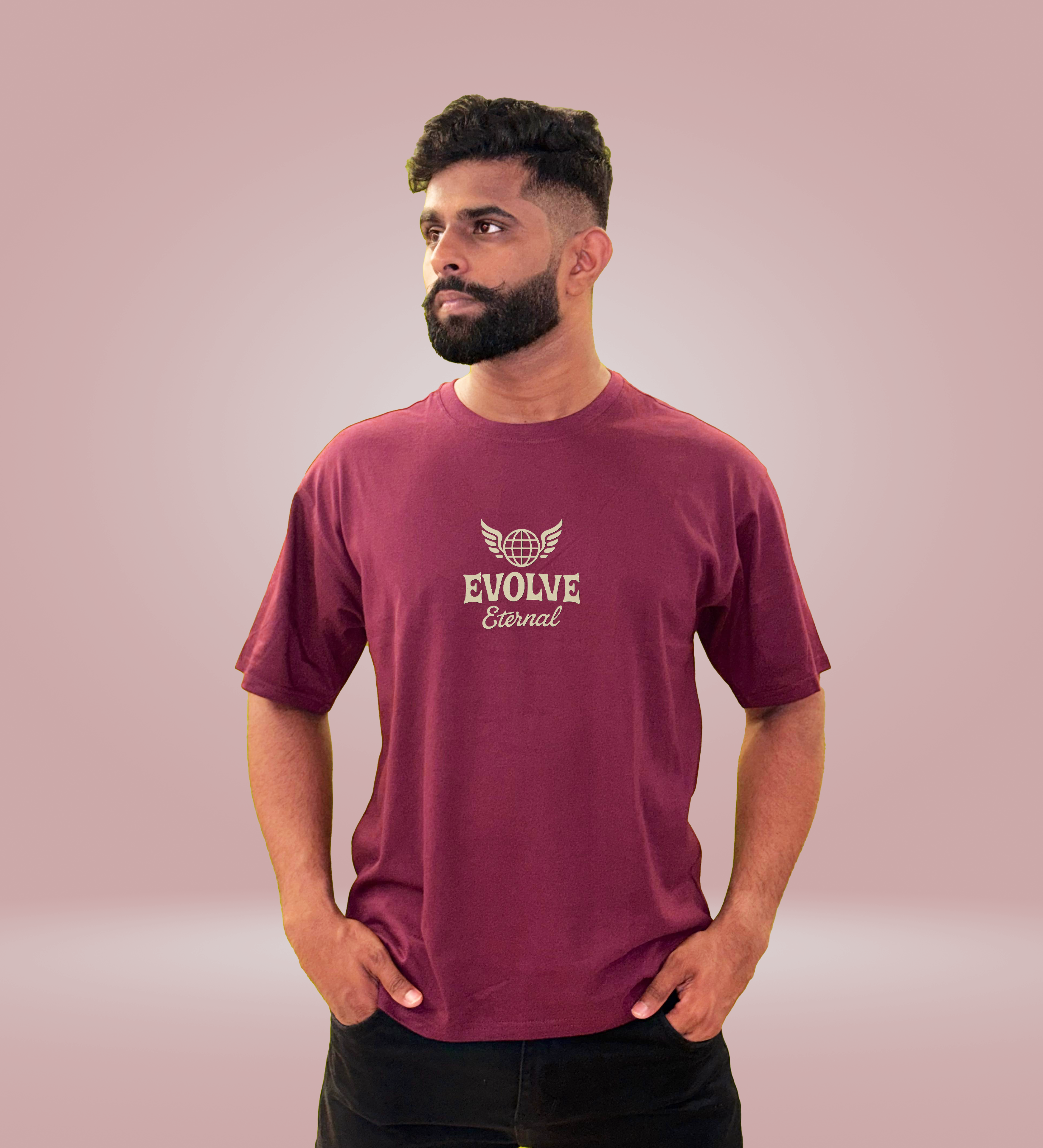 Front view of maroon oversized T-shirt with "Evolve Eternal" text, worn by man with hands in pockets.