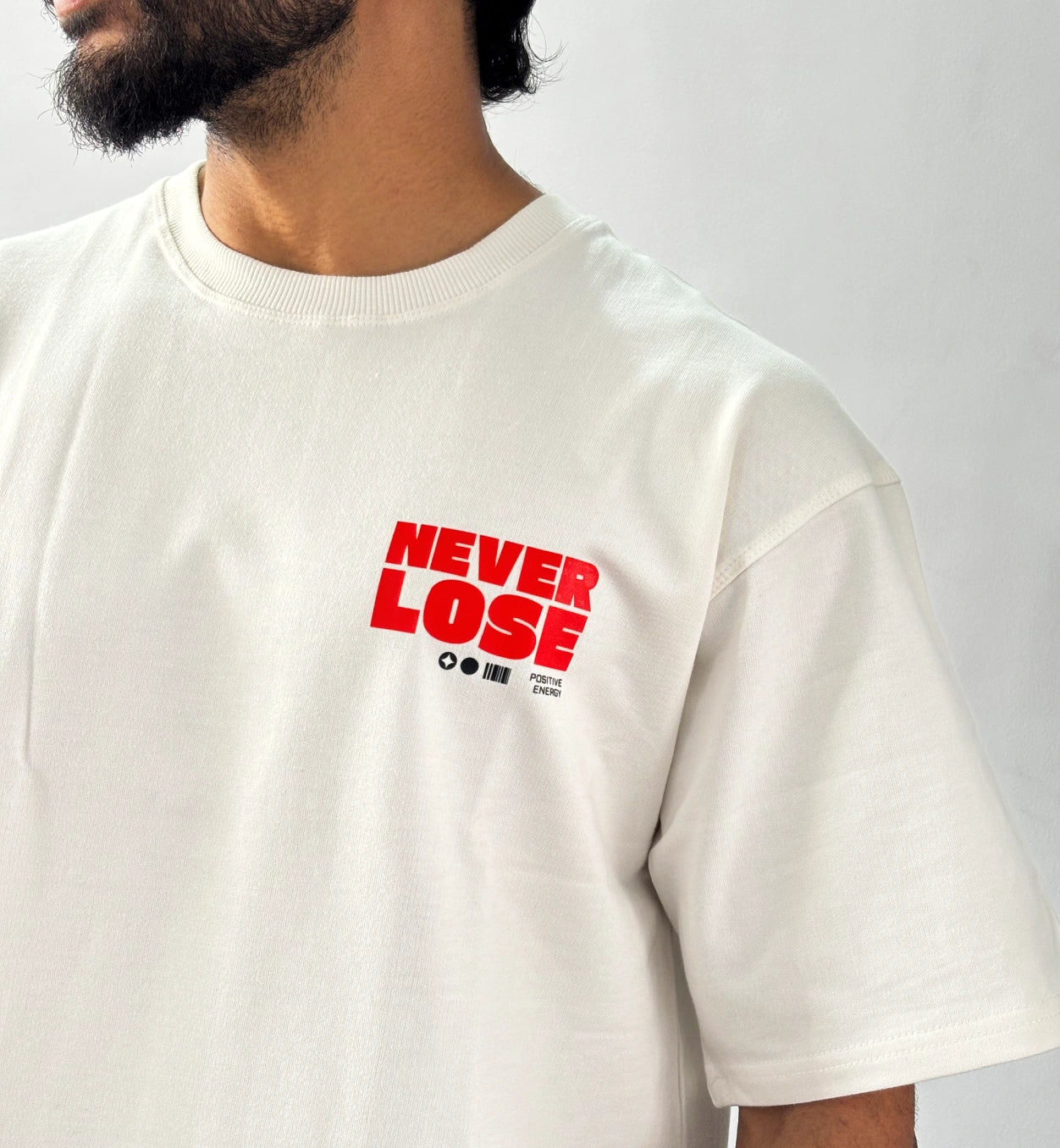 Close-up of red Never Lose chest print on oversized cream streetwear T-shirt