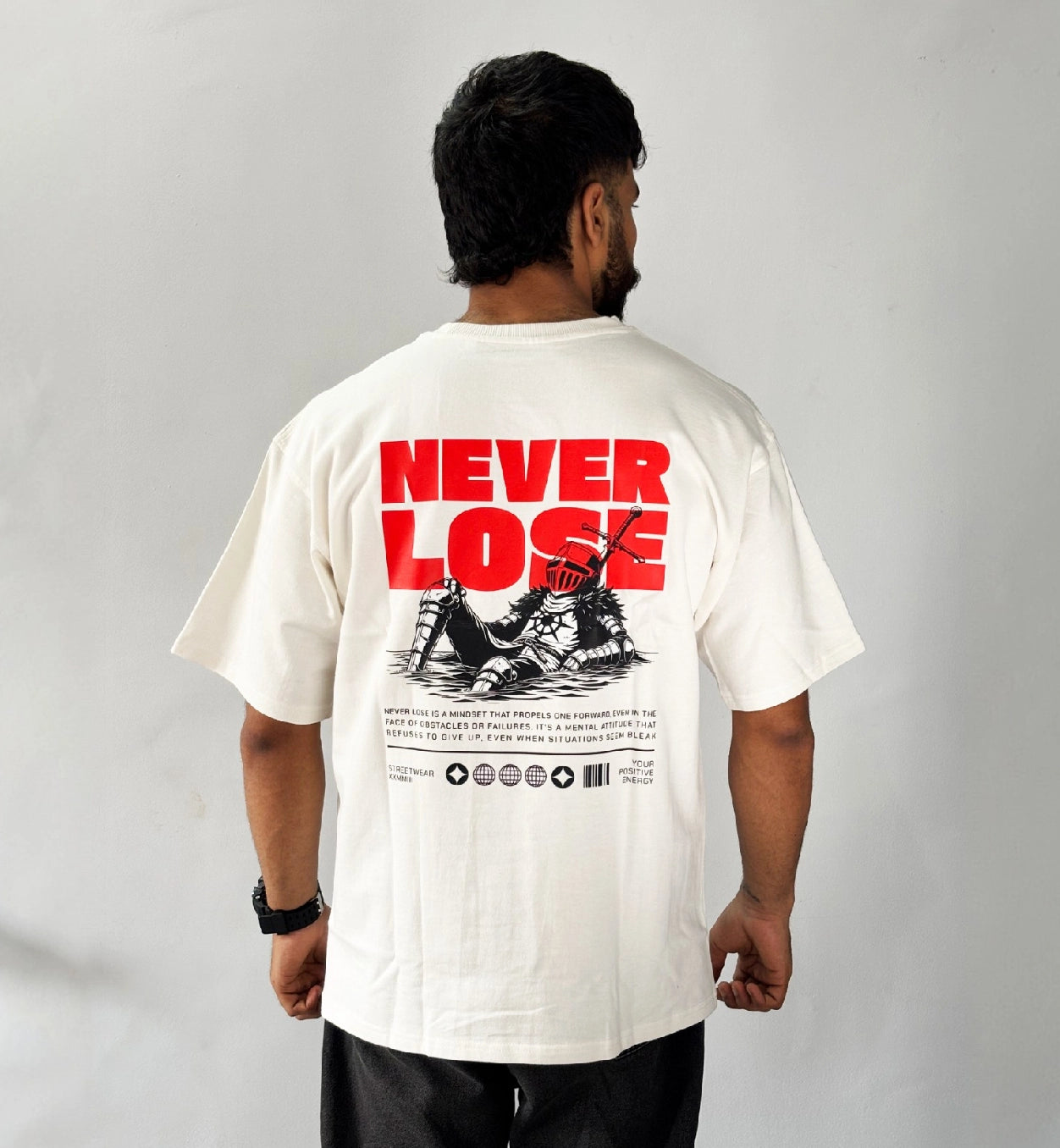 Oversized cream graphic T-shirt back view with bold red “Never Lose” text and warrior illustration streetwear design