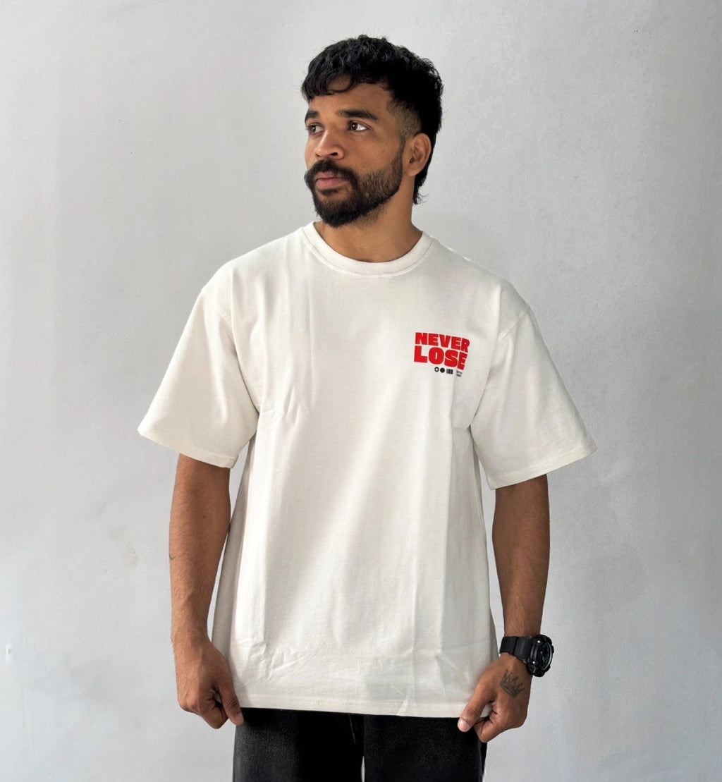 Male model wearing oversized cream Never Lose graphic T-shirt with minimalist red chest print streetwear style