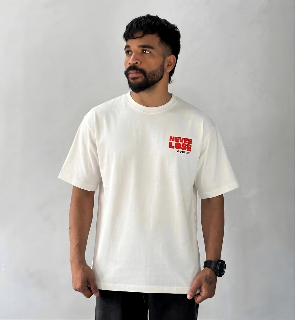 Male model wearing oversized cream Never Lose graphic T-shirt with minimalist red chest print streetwear style
