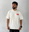 Male model wearing oversized cream Never Lose graphic T-shirt with minimalist red chest print streetwear style