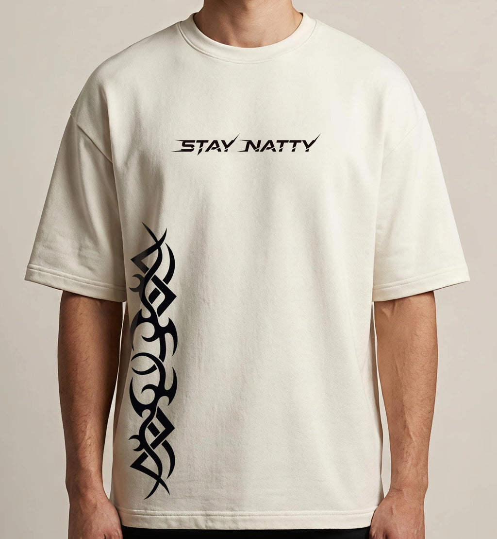Man wearing off-white oversized Stay Natty t-shirt with minimal chest typography and bold black tribal side graphic design